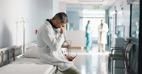 Stress, grief or mistake with a mature doctor in a hospital looking unhappy for healthcare or...
