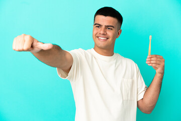 Fototapeta premium Young handsome man brushing teeth over isolated blue background giving a thumbs up gesture