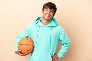 Handsome young basketball player man isolated on ocher background posing with arms at hip and...