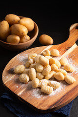 Food concept Spot focus homemade gnocchi on wooden board on black background with copy space