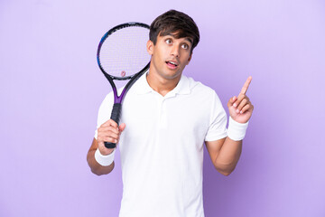 Handsome young tennis player man isolated on ocher background thinking an idea pointing the finger...