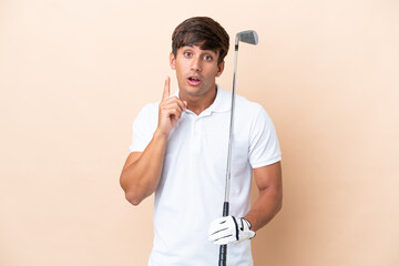 Young golfer player man isolated on ocher background intending to realizes the solution while...