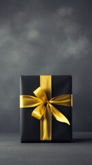 Black gift box and golden ribbon on black background.
