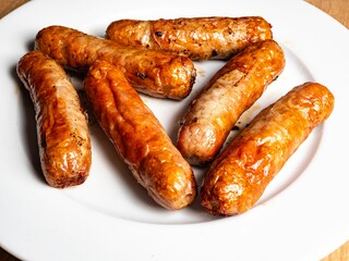 Pork Sausage on a white plate a closeup of a number of cooked meaty sausage