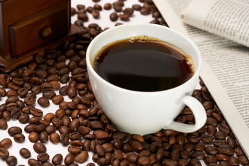 Black coffee and coffee beans on newspaper