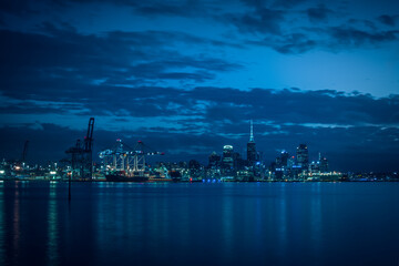 Bright lights of Auckland downtown at night. Dramatic view over Auckland City from North Shore