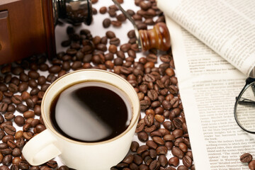 Black coffee and coffee beans on newspaper