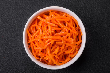 Delicious spicy carrots sliced and cooked in Korean style on a ceramic plate