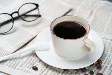 Black coffee and coffee beans on newspaper