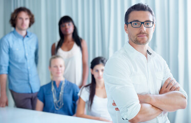 Fototapeta premium Leader with team, creative and people at startup, portrait at agency with designer and support, trust in mission. About us, solidarity and collaboration, serious male leadership with arms crossed