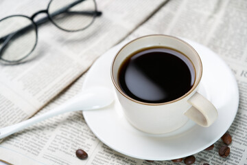 Black coffee and coffee beans on newspaper