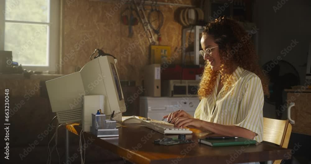 Leinwandbilder Hispanic Female Software Engineer Programming On Old Desktop Computer In Retro Garage With Random Appliances. Young Woman Starting Fintech Startup Company In Nineties. Nostalgia Concept. Zoom Out Shot