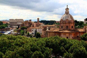 Fototapeta na wymiar Photo of a panoramic view of the historic part of the city with a church and the Colosseum in the background and green areas in the foreground in the city of Rome, Lazio region, Italy