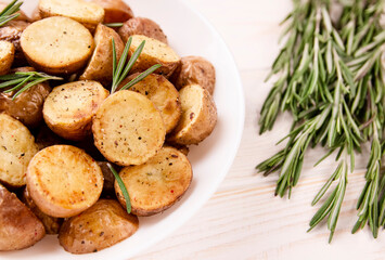 Delicious baked potatoes with rosemary on a light background