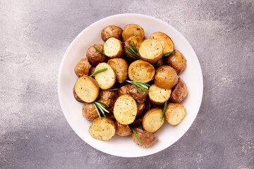 Delicious baked potatoes with rosemary on a gray background