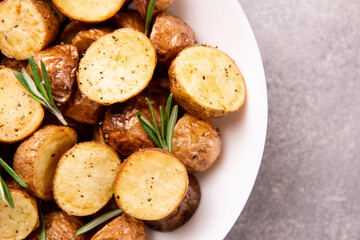 Delicious baked potatoes with rosemary on a gray background