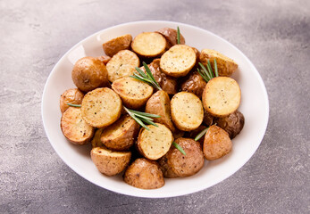 Delicious baked potatoes with rosemary on a gray background
