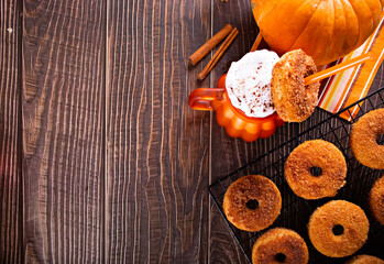 Pumpkin spice whipped latte in glass. Hot autumn drink beverage. Nearby delicious apple cider donuts.