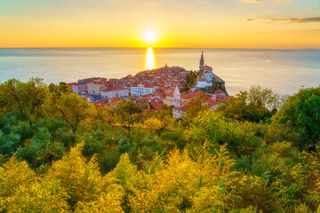 Piran Old Town, Slovenia, scenic cityscape. Top view of medieval architecture with church of St. George, Adriatic Sea and sky in sunset light from Old City Walls, outdoor travel background