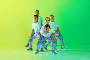 Papier Peint photo École de danse Team of smiling attractive girls children dressed in fashion, stylish outfit dancing in choreography class isolated on green-yellow gradient background.