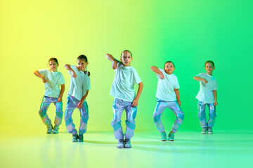 Group of girls wearing sporty trendy outfit with bright glittered makeup dancing synchronous in...