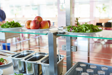Plates of apples and salad leaves on glass shelf