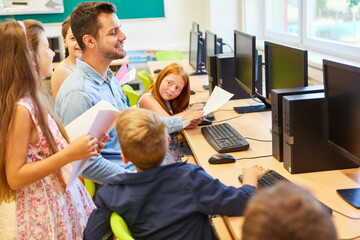 Smiling teacher with students in computer class