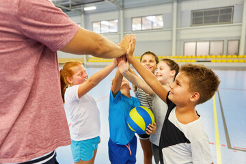 Happy students giving high five to coach in gym class - obrazy, fototapety, plakaty