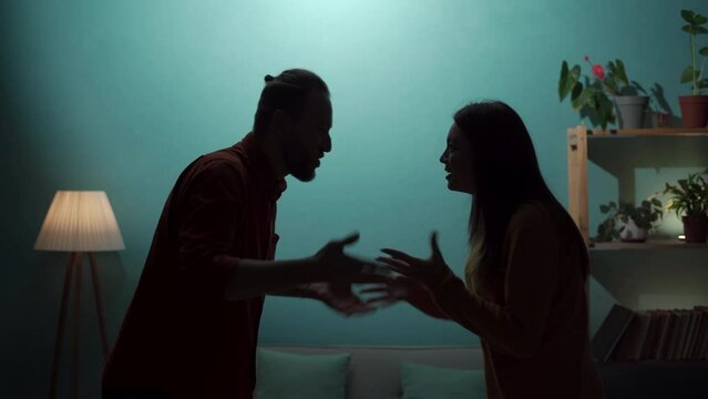 Angry man and woman are arguing in the living room. Silhouette of aggressive nervous couple arguing at home