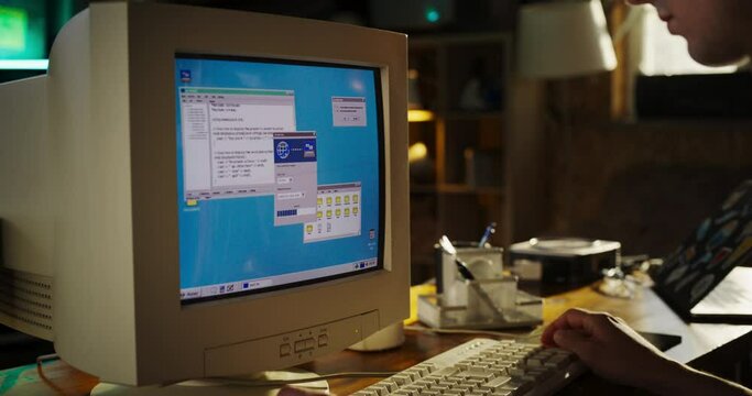 Zoom In Shot Of Caucasian Male College Student Using Old Desktop Computer In Nineties Retro Garage. Young Programmer Connecting World Wide Web Via Early Internet Software, Exploring Global Network.