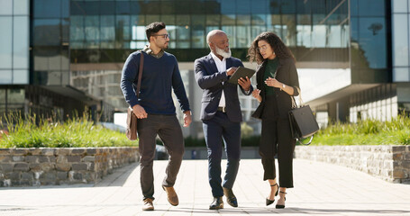 Walking, talking and business people with a tablet in the city for planning, meeting or discussion. Teamwork, corporate and employees speaking with technology for a strategy, internet or email