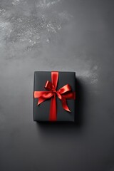 Christmas gift box with red ribbon on black background.