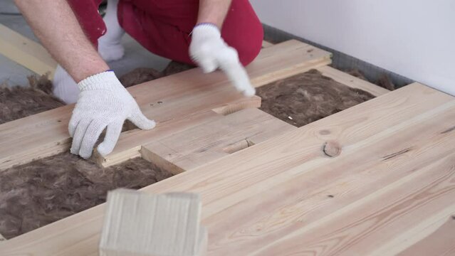 woodworking in the house - a young professional male mounts a pine wood floor