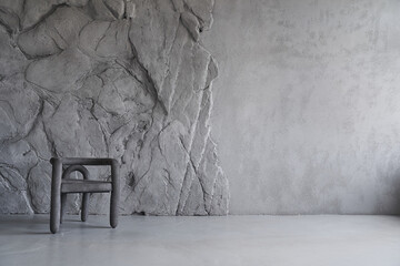 Modern interior with an elegant chair against a gray, rough, uneven wall with space to copy. High quality photo