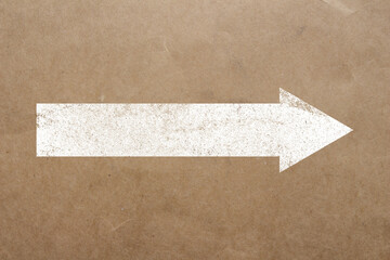 White arrow shape printed on recycled paper. Copy space.