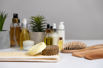 Obraz na płótnie Canvas Natural eco-friendly cosmetics for hair care - solid shampoo, hair oils, wooden combs. Top view on white background.