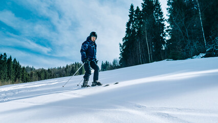 Skier on piste running downhill in beautiful Alpine landscape. Blue sky on background. Free space...