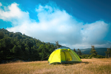 A green tent set up among clouds and greenery. A peaceful camp where you can spend time in touch with nature.