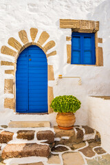 Typical white Greek house with blue door and window in Plaka village, Milos island, Cyclades, Greece