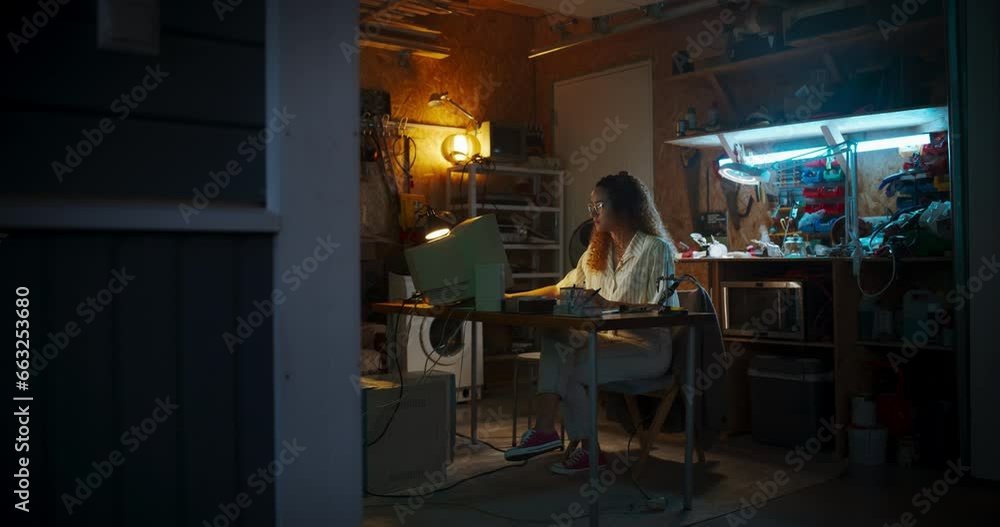 Aufkleber wide shot of hispanic female engineer using old computer in nineties retro garage in the evening. sm