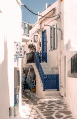 Fototapeta na wymiar Vibrant alleyway with blue and white buildings decorated with flowers