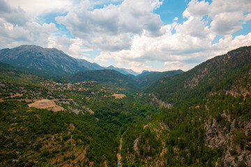 Obraz premium Cliff on a mountain plateau with rocks, mountains and grass in the foreground against a low cloudy blue sky located in Turkey.
