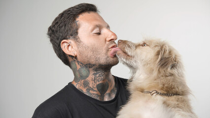 Cute dog lick owner face. Young adult man kiss pet close up. Happy person portrait with best...