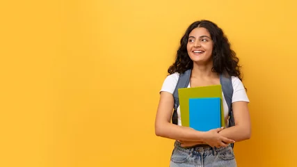Fototapeten Young smiling happy indian woman student on yellow © Prostock-studio
