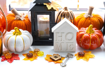 Cozy autumn decor on the windowsill with pumpkins, autumn leaves, a house and keys - autumn mood,...