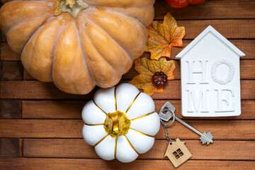 Cozy layout on a wooden background of slats with pumpkins, autumn leaves, a house and keys - autumn...