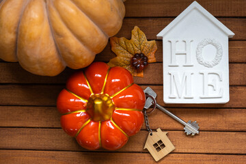Cozy layout on a wooden background of slats with pumpkins, autumn leaves, a house and keys - autumn...