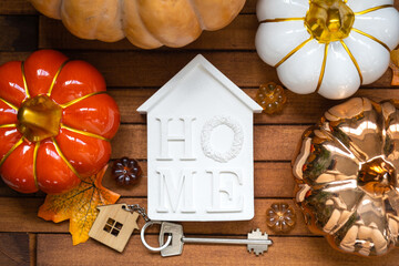 Cozy layout on a wooden background of slats with pumpkins, autumn leaves, a house and keys - autumn...