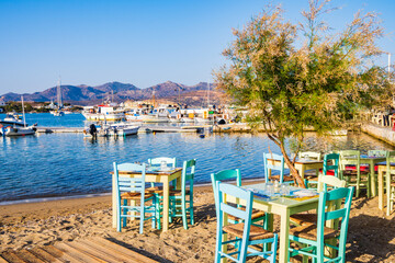 Tables and chairs in typical Greek taverna restaurant in Pollonia port, Milos island, Cyclades, Greece
