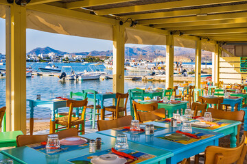 Tables and chairs in typical Greek taverna restaurant in Pollonia port, Milos island, Cyclades, Greece - 663261868